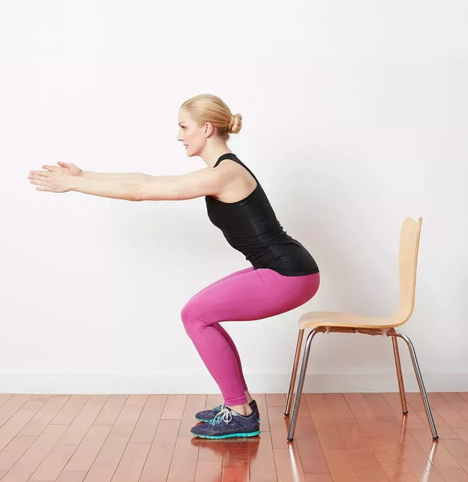 A woman uses a chair for Squat